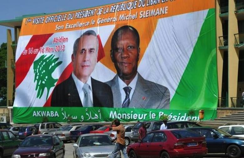 People walk on March 12, 2013 past a poster bearing the portraits of Ivory Coast President Alassane Outtara (R) and his Lebanese counterpart Michel Sleiman on the Republic Square in Abidjan. AFP/Sia Kambou